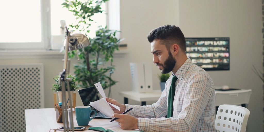 a man sitting at a desk with a laptop and papers