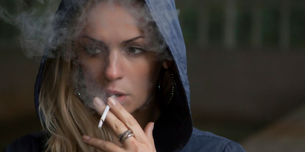 woman wearing hoodie while holding cigarette