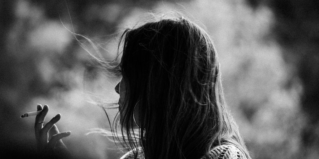 a woman smoking a cigarette in a black and white photo