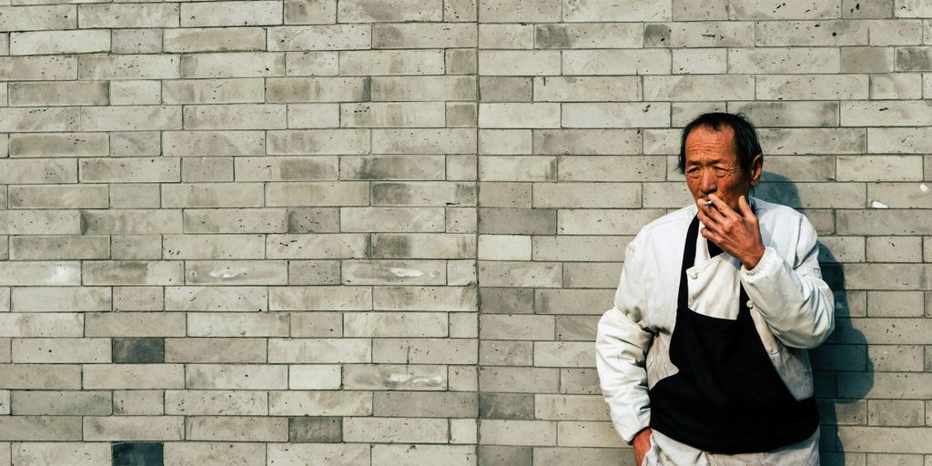 man in white dress shirt leaning on gray brick wall