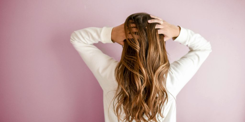 woman in white long-sleeved shirt standing in front of pink wall