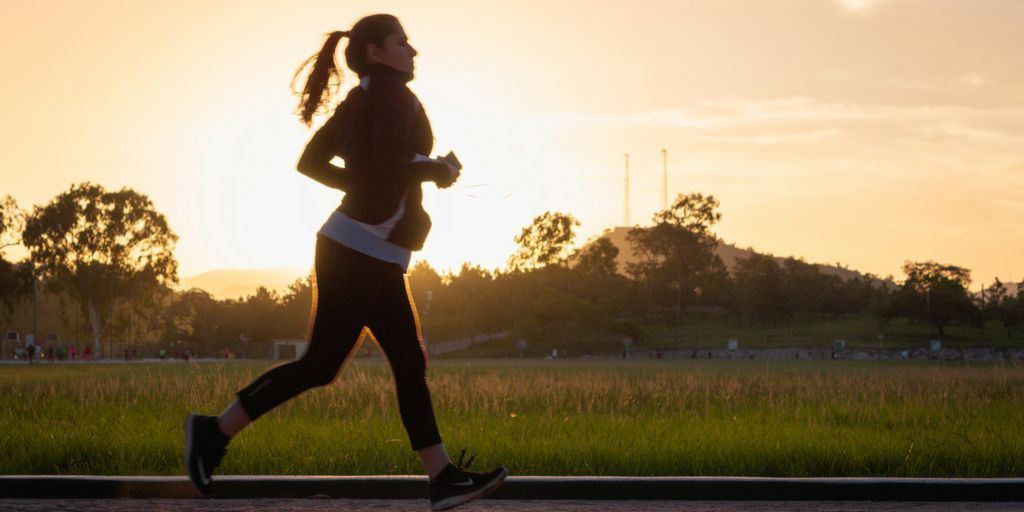 woman in black sports bra and black pants running on water during sunset