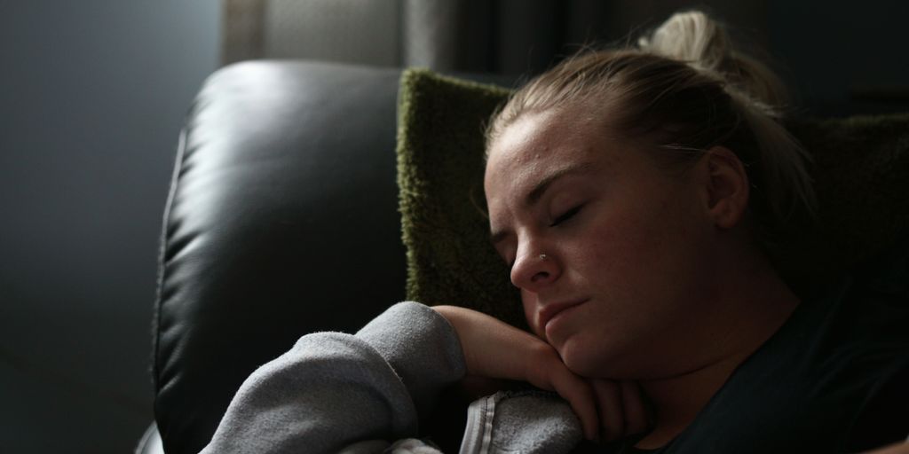 boy in gray hoodie lying on black leather couch